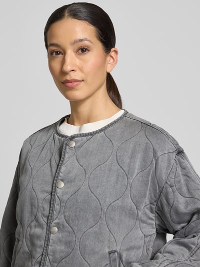 Frauenmodel trägt Regular Fit Jacke aus reinem Lyocell Modell 'Alina' von CARS JEANS in grauer Stepp-Optik mit Rundhalsausschnitt, sichtbarer Knopfleiste und Eingrifftaschen, strukturierte Textur, Nahaufnahme Oberkörper. Rückenlänge 58 cm, Schulterbreite 49 cm, Brustweite 53 cm, Ärmellänge 53 cm bei Größe S.