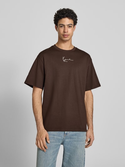 Männermodel trägt Regular Fit T-Shirt mit Logo-Stitching von KARL KANI, braun, Rundhalsausschnitt, Kurzärmelig, Rückenlänge 74 cm bei Größe M, Ganzkörperansicht von vorne.