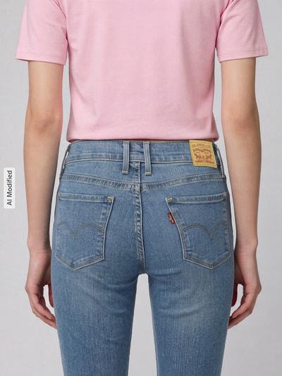 Frauenmodel trägt Skinny Fit Jeans aus Baumwoll-Mix Modell '311 seamed' von Levi's® 300 in hellblau, Ganzkörperansicht Rückansicht, KI-modifiziertes Bild.
