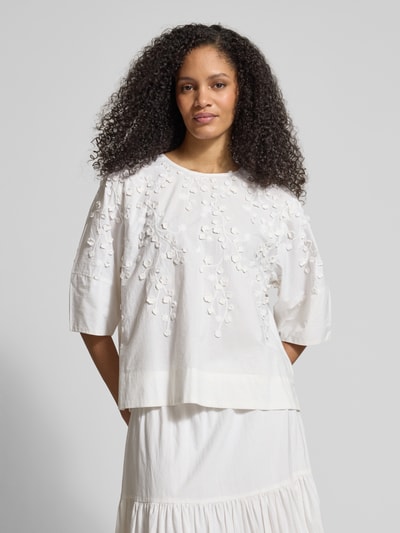 Frauenmodel trägt Bluse mit floraler Zier-Applikation von JAKE*S STUDIO WOMAN, weiß, lockere Passform, Rundhalsausschnitt, Ganzkörperansicht von vorne.