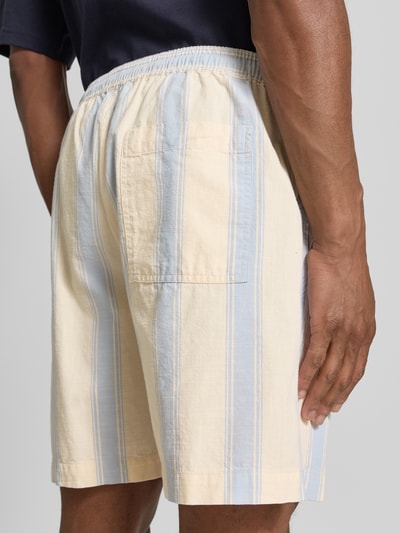 Männermodel trägt Regular Fit Shorts aus reiner Baumwolle von Armedangels mit gestreiftem Allover-Muster und elastischem Bund, Ganzkörperansicht Rückansicht.