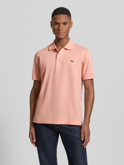 Männermodel trägt Regular Fit Poloshirt aus Baumwoll-Mix von Lacoste in Rosa, Piqué-Struktur, Logo-Detail, V-Ausschnitt, Nahaufnahme Oberkörper.