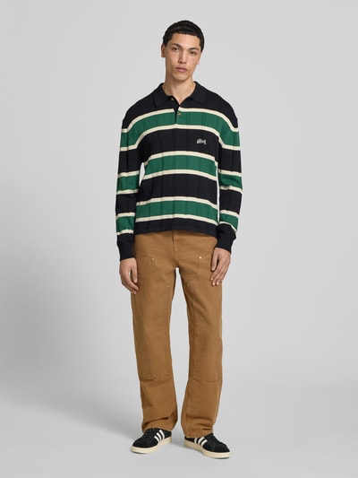 Männermodel trägt Strickpullover mit Polokragen und Label-Stitching von BLKVIS in Dunkelblau mit grünen und weißen Streifen, Reine Baumwolle, Regular-Fit, Zopfmuster, Knopfleiste, Rückenlänge 66 cm, Ärmellänge 72 cm, Ganzkörperansicht von vorne.