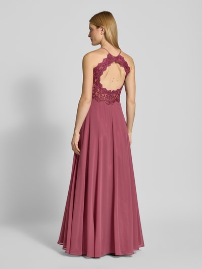 Modelka kobieca ma na sobie 'Abendkleid mit Spitze und Cut Out' od V.M., kolor różowy, koronka, szyfon, A-linia, maxi, cut out na plecach, zamek, długość tyłu 143 cm, szerokość w rozmiarze 36: 35 cm, widok całopostaciowy z tyłu.