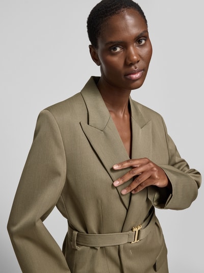 Frauenmodel trägt Longblazer aus Woll-Mix von Victoria Beckham in Olive mit Taillengürtel, Pattentaschen, taillierter Passform, Nahaufnahme Oberkörper.