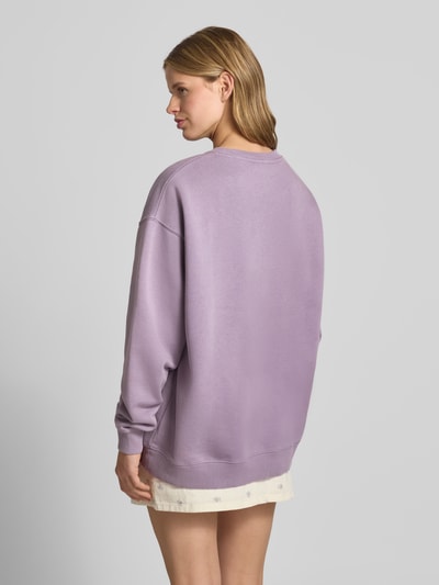 Frauenmodel trägt Oversized Sweatshirt mit Rundhalsausschnitt und Logo von OH APRIL, lila, aus Baumwoll-Mix, Ganzkörperansicht Rückansicht.