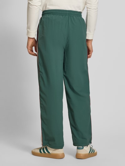 Männermodel trägt grüne Trackpants mit Label-Stitching Modell 'SLIPSTREAM' von PROHIBITED, elastischer Bund, Relaxed Fit, Ganzkörperansicht Rückansicht.