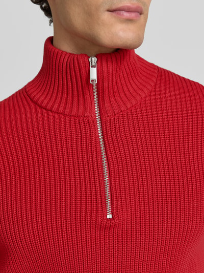 Männermodel trägt Slim Fit Strickpullover aus reiner Baumwolle mit Troyer-Kragen von MCNEAL, Struktur in Rot, Nahaufnahme Oberkörper.
