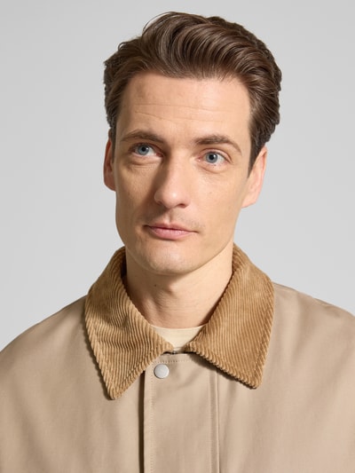 Männermodel trägt Regular Fit Jacke aus reiner Baumwolle Modell 'KYLE' von SELECTED HOMME in Beige mit Umlegekragen, Nahaufnahme Oberkörper.