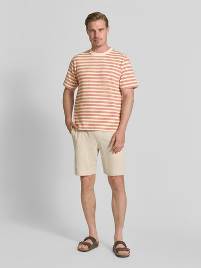 Männermodel trägt Regular Fit T-Shirt aus Baumwoll-Mix Modell 'ELI' von Selected Homme, gestreift in Beige und Rosa, Herren T-Shirt, Ganzkörperansicht von vorne.