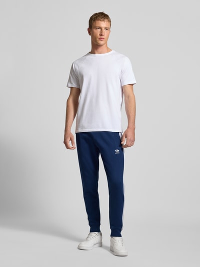 Männermodel trägt Sweatpants mit elastischem Bund von adidas Originals, Baumwoll-Mix, Lockerer-Schnitt, Eingrifftaschen, Ganzkörperansicht von vorne.
