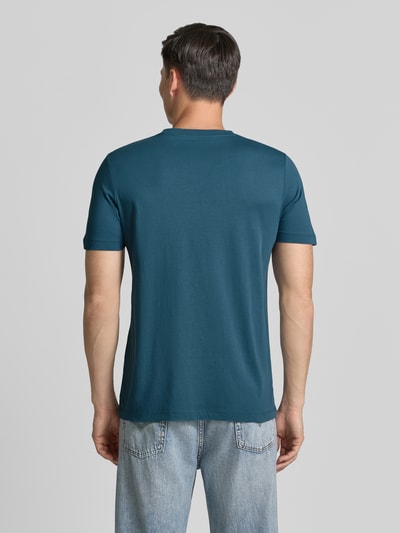 Männermodel trägt Regular Fit T-Shirt aus reiner Baumwolle von s.Oliver RED LABEL in Uni-Blau, glatte Jersey-Textur, Ganzkörperansicht Rückansicht.