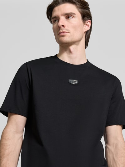 Männermodel trägt T-Shirt mit Label-Detail von Antony Morato in Schwarz, reine Baumwolle, Regular Fit, Nahaufnahme Oberkörper.