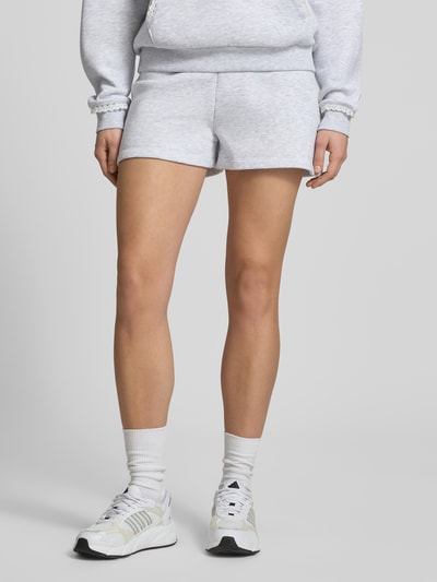 Frauenmodel trägt Regular Fit Sweatshorts mit Spitzenbesatz von Review, heller Material-Mix mit Baumwoll-Anteil, Ganzkörperansicht von vorne.