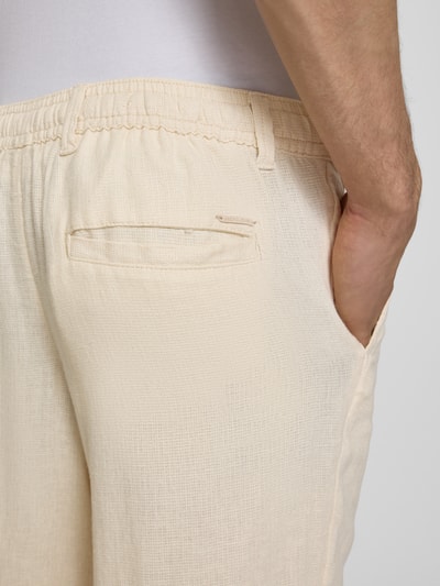 Männermodel trägt cremefarbene Leinenhose mit Bindegürtel Modell 'KARL MYKONOS' von Jack & Jones, Leinen-Viskose-Mix, Nahaufnahme Hüfte. Kontext: Relaxed-Fit, Knopf-und Reißverschluss, französische Eingrifftaschen, Gesäßleistentasche, Bundweite bei Größe M 41 cm, Innenbeinlänge bei Größe M 78 cm.