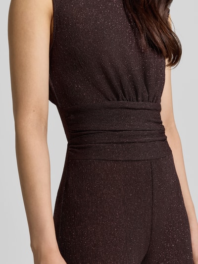 Frauenmodel trägt Jumpsuit mit Raffungen von Rinascimento in Dunkelbraun mit Glanz, taillierte Passform, Material-Mix, Nahaufnahme Oberkörper.