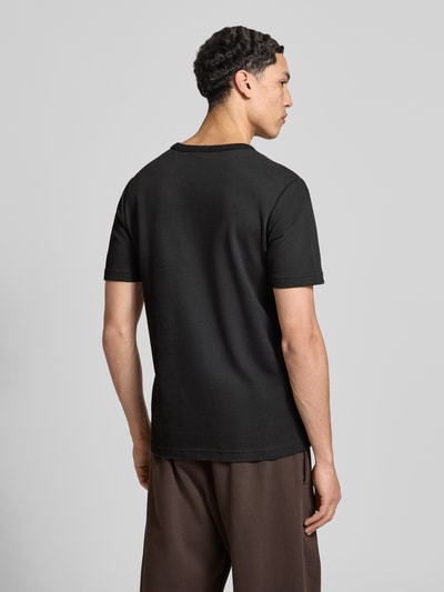 Männermodel trägt Regular Fit T-Shirt mit Baumwoll-Anteil von adidas Originals in Schwarz, Waffelstruktur, unifarben, Ganzkörperansicht Rückansicht.