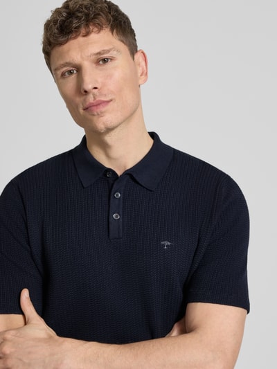 Männermodel trägt Regular Fit Poloshirt in Strick-Optik von Fynch-Hatton, dunkelblau, Baumwoll-Mix, Logo-Stitching, Nahaufnahme Oberkörper.
