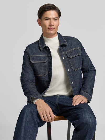 Männermodel trägt Rollkragenpullover mit Viskose-Anteil von MARKUP in Weiß, gerade Passform, unter Jeansjacke, Nahaufnahme Oberkörper.
