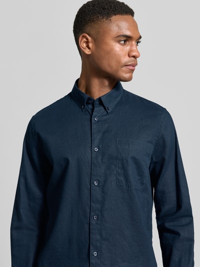 Męski model nosi Regular Fit Freizeithemd mit Leinen-Anteil od Matinique, mieszanka lnu i bawełny, kołnierzyk typu button down, listwa guzikowa, brustasza, długość tyłu w rozmiarze M: 64 cm, szerokość ramion w rozmiarze M: 43 cm, długość rękawów w rozmiarze M: 68 cm, ciemnogranatowy materiał o gładkiej strukturze, widoczna tekstura, nahaufnahme górnej części ciała