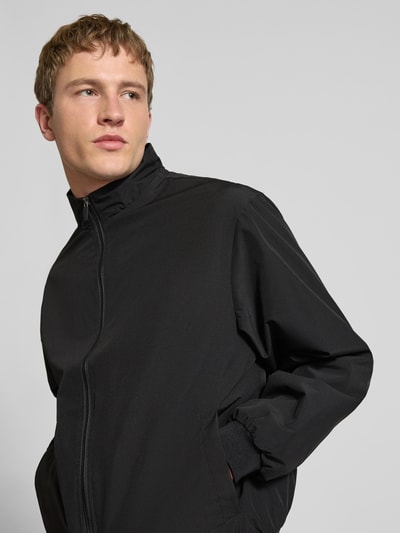 Männermodel trägt zwarte Regular fit jack met opstaande kraag Model 'Charge' van JACK & JONES met ritssluiting en steekzakken, Nahaufnahme Oberkörper.