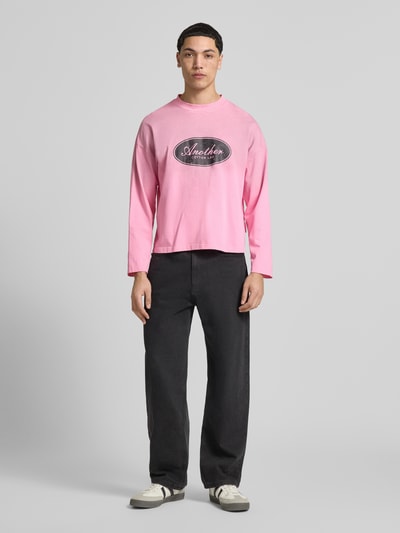 Männermodel trägt Relaxed Fit Longsleeve aus Baumwolle Modell 'Another Vintage' von ANOTHER COTTON LAB in Rosa mit Label-Print, Reine Baumwolle, Stehkragen, Rückenlänge bei Größe M 63 cm, Ganzkörperansicht von vorne.