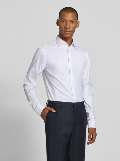 Männermodel trägt weißes Slim Fit Businesshemd mit extra langem Arm von Jake*s, glatte Struktur, Ganzkörperansicht von vorne.