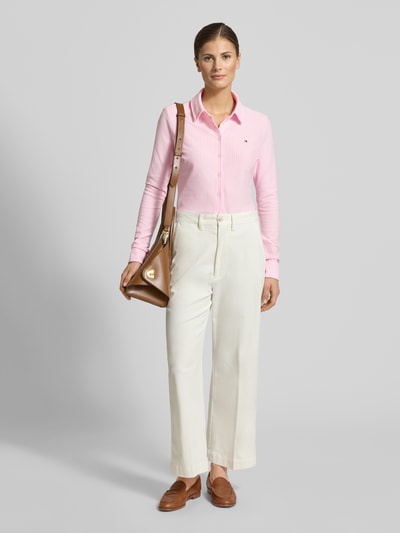 Vrouwenmodel draagt Slim Fit Hemdbluse uit katoenmix van Tommy Hilfiger, gestreept all-over motief, overhemdkraag, lange mouw, knoopsluiting, gestikt logo, mouwboord, kleur lichtroze, gladde textuur. Ganzkörperansicht van voren.