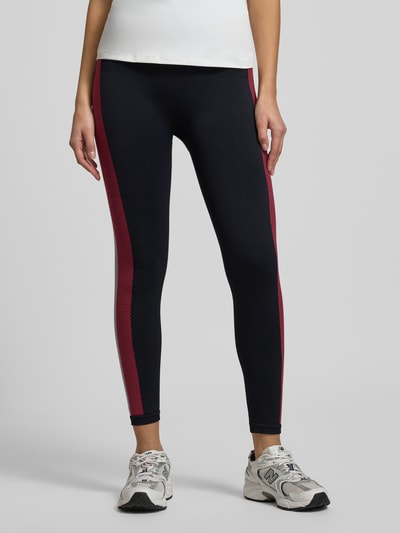 Frauenmodel trägt Leggings mit Galonstreifen Modell 'SEAMLESS' von Tommy Hilfiger, dunkel mit roten Streifen, Material-Mix, eng anliegend, elastischer Bund, Ganzkörperansicht von vorne.