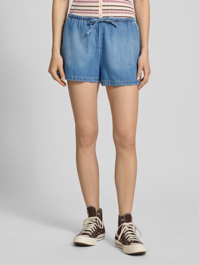 Frauenmodel trägt Wide Leg Jeansshorts aus Baumwoll-Lyocell-Mix Modell 'ARIA' von Only in Denim-Optik mit Kontrastnähten, elastischem Bund und seitlichen Eingrifftaschen, Ganzkörperansicht von vorne.