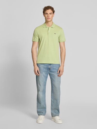 Männermodel trägt Regular Fit Poloshirt aus Baumwoll-Mix von Lacoste in Hellgrün, unifarben, Logo-Detail, Piqué-Textur, Ganzkörperansicht von vorne.