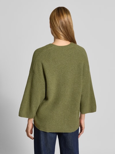 Männermodel trägt zielony kardigan z elastycznej mieszanki materiałów z bawełną, krój oversized fit, imitacja dzianiny, Model 'DAMSVILLE' od American Vintage, listwa guzikowa, dekolt w serek, długość tyłu 63 cm, długość rękawów 35 cm, widok całej sylwetki z tyłu