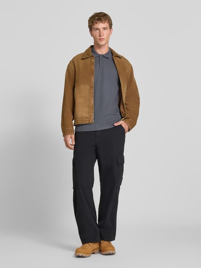 Mężczyzna model nosi koszulkę polo Slim Fit Poloshirt mit Label-Stitching Modell 'AUSTIN' von JACK & JONES, mieszanka materiałów ze stretchową bawełną, kołnierzyk polo, wyhaftowane logo, długość tyłu w rozmiarze M: 70 cm, krój slim fit, kolor ciemnoszary, widok całej sylwetki z przodu.
