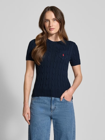 Frauenmodel trägt Slim Fit Kurzarmpullover mit Label-Stitching von Polo Ralph Lauren in Dunkelblau, Baumwolle, Strick-Optik, Brusttasche, Logo-Stitching, Rundhalsausschnitt, elastische Abschlüsse, kombiniert mit blauer Jeans, Ganzkörperansicht von vorne.