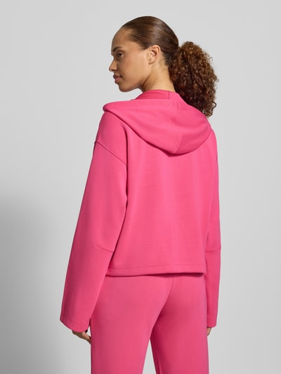 Frauenmodel trägt Regular Fit Sweatjacke mit Modal-Anteil von Christian Berg Woman in kräftigem Pink, strukturierte Oberfläche, Elastik-Material-Mix, Kapuze, Ganzkörperansicht Rückansicht, geteilter Känguru-Tasche und Tunnelzug.