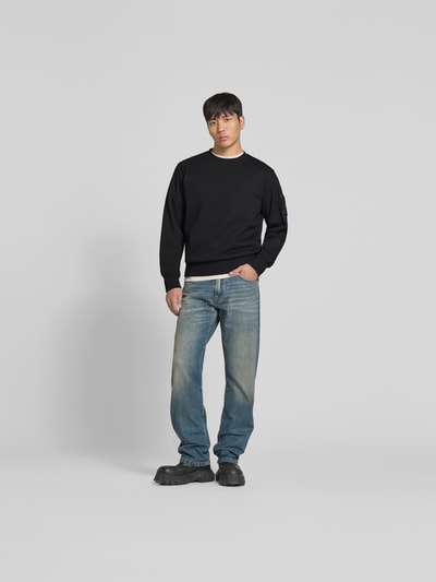 Männermodel trägt Sweatshirt mit Rundhalsausschnitt von Moose Knuckles in Schwarz aus reiner Baumwolle, Regular-Fit, Logo-Detail, Ganzkörperansicht von vorne.