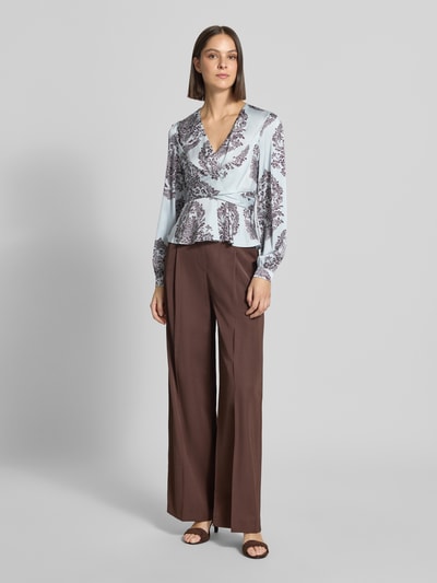 Vrouwenmodel draagt blouse met peplum-zoom Model 'Rista' van Neo Noir, v-hals, getailleerd, met lange mouwen, lichtblauw met bruine print, ruglengte maat 36: 55 cm, mouwlengte maat 36: 65 cm, dames blouse, volledige lichaamsaanzicht voorkant.