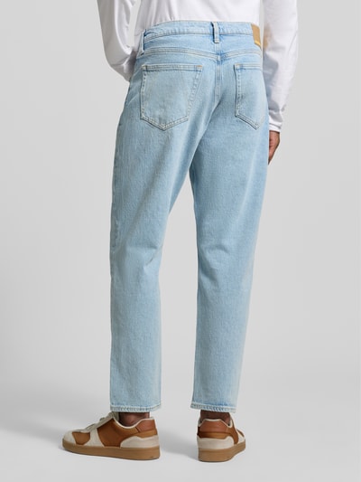 Mannelijk model draagt lichte denim Tapered Fit Jeans uit biologisch katoen-mix model 'MAAKX' van Armedangels, 5-pocket-design, label patch, riemlussen, mid waist, relaxed tapered fit, knoop- en ritssluiting, achteraanzicht volledige lichaamsopname.