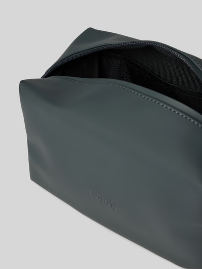 Produktfoto, Kulturtasche mit Label-Prägung von Rains in Dunkelgrau, glatte Oberfläche, sichtbares Hauptfach, Steckfächer innen, Detailaufnahme, Maße 20x13x11 cm