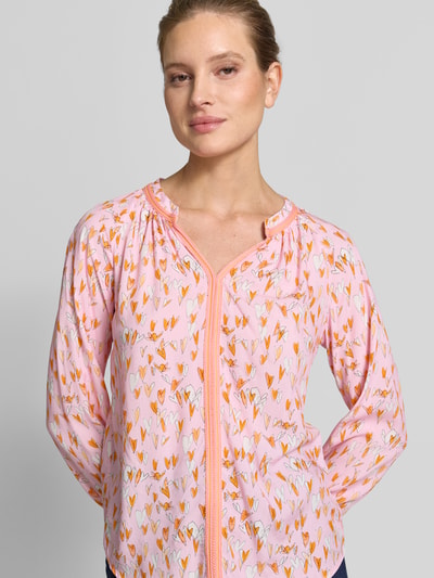 Frauenmodel trägt Regular Fit Bluse aus Viskose mit V-Ausschnitt von Emily Van den Bergh in Rosa mit Allover-Herzmotiv, Nahaufnahme Oberkörper.