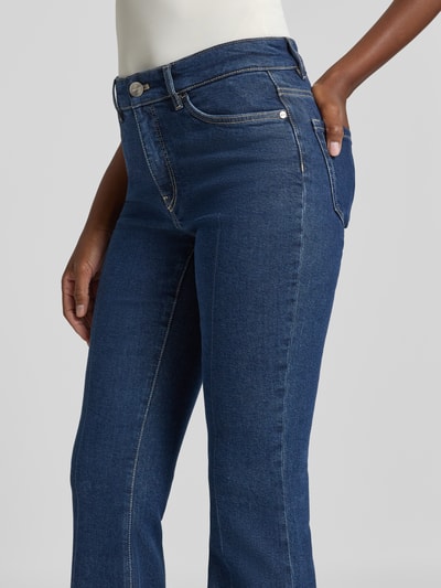 Frauenmodel trägt Feminine Fit Jeans mit Eingrifftaschen von Marc Cain aus dunkelblauem Baumwoll-Mix mit Lyocell, Nahaufnahme Oberkörper.
