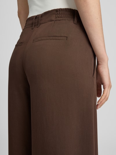 Frauenmodel trägt Barrel Fit Hose mit Gesäßtaschen Modell 'DUTIFUL' von DRYKORN in Braun, reine Baumwolle, Detailaufnahme Rückansicht.