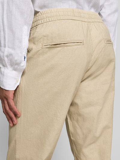 Męski model nosi Straight Fit Leinenhose mit elastischem Bund Modell 'Barton' von Matinique, mieszanka lnu i bawełny, beżowe, kieszenie z tyłu, widok z tyłu zbliżenie. Szerokość w rozmiarze M: 34 cm, długość wewnętrzna nogawki: 78 cm.