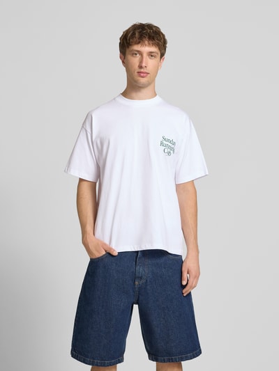 Männermodel trägt weißes Herren T-Shirt mit Statement-Print Modell 'Sunday Running Club' von ANOTHER COTTON LAB aus Reine Baumwolle, Boxy-Fit, Rundhalsausschnitt, Rückenlänge bei Größe M 69 cm, Ganzkörperansicht von vorne.