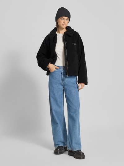 Frauenmodel trägt schwarze Jacke aus Teddyfell mit Label-Stitching Modell 'LAJA' von Pegador, Reißverschluss, Umlegekragen, Ganzkörperansicht von vorne.