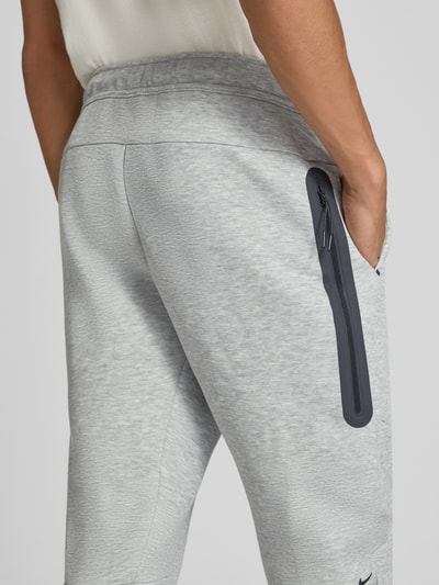 Männermodel trägt hellgraue Slim Fit Sweathose aus Baumwoll-Mix von Nike, sichtbarer Reißverschluss, Detailaufnahme, Herren Sweathose von Nike.