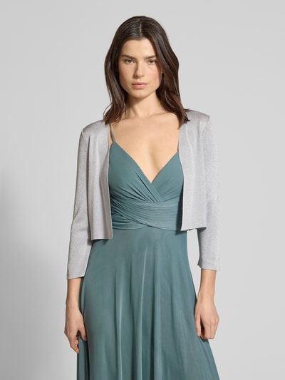 Frauenmodel trägt Regular Fit Bolero aus Viskose-Mix in Strick-Optik von Jake*s Cocktail in Glitzer-Optik, Ganzkörperansicht von vorne, Rückenlänge bei Größe 36: 39 cm.