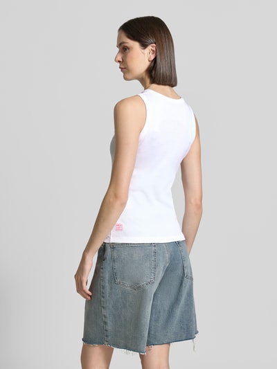 Frauenmodel trägt Tanktop mit Motiv-Print und Ziersteinbesatz von Marc Cain aus Baumwoll-Elasthan-Mix, Slim-Fit, Rückenlänge 55 cm, Ganzkörperansicht Rückansicht.