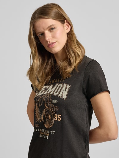 Modelka kobieca ma na sobie damski t-shirt Regular Fit T-Shirt aus reiner Baumwolle Modell 'LUCY' od ONLY, jednokolorowy, nadruk z motywem, okrągły dekolt, krótki rękaw ze zrolowanym brzegiem, wykończenie dżersej, z czystej bawełny, widok na górną część ciała z przodu.