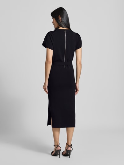 Vrouwenmodel draagt Slim Fit midi-jurk uit viscosemix Model 'JULIANY' van Ted Baker, effen zwart, met riem, ruglengte maat 36 110 cm, borstwijdte 37 cm, mouwlengte 14 cm, geheel zwarte look, textuur glad, mat, met korte mouwen, ronde hals, geïntegreerde riem, rugaanzicht, dames midi-jurk van Ted Baker, viscosemix, slim fit, korte mouw, model 'JULIANY', geïntegreerde riem, rugaanzicht.